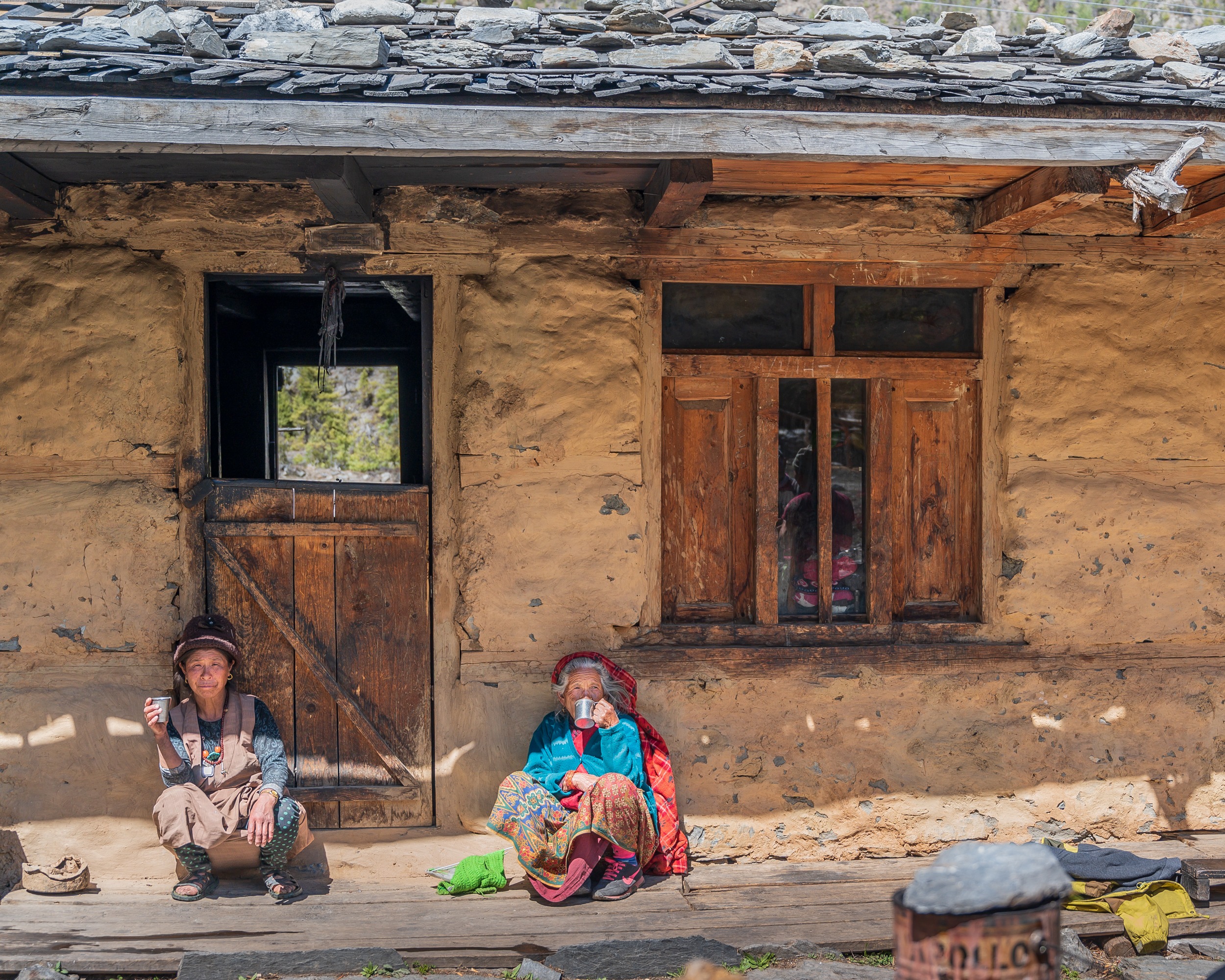 two women sitting in shade in Nepal drinking tea