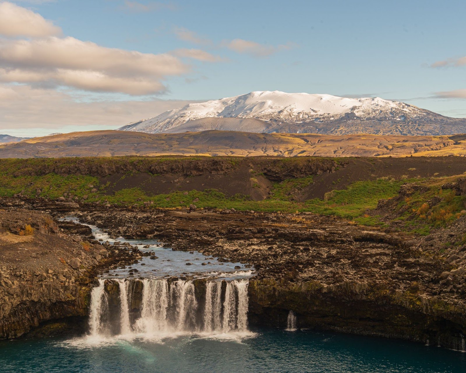 A waterfall with a mountain in the background Iceland